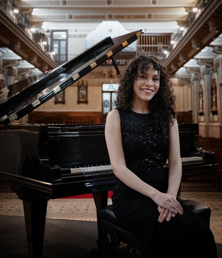 Pianista sentada ao piano de cauda em uma sala de concertos